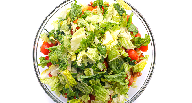 adding chopped romaine to bowl